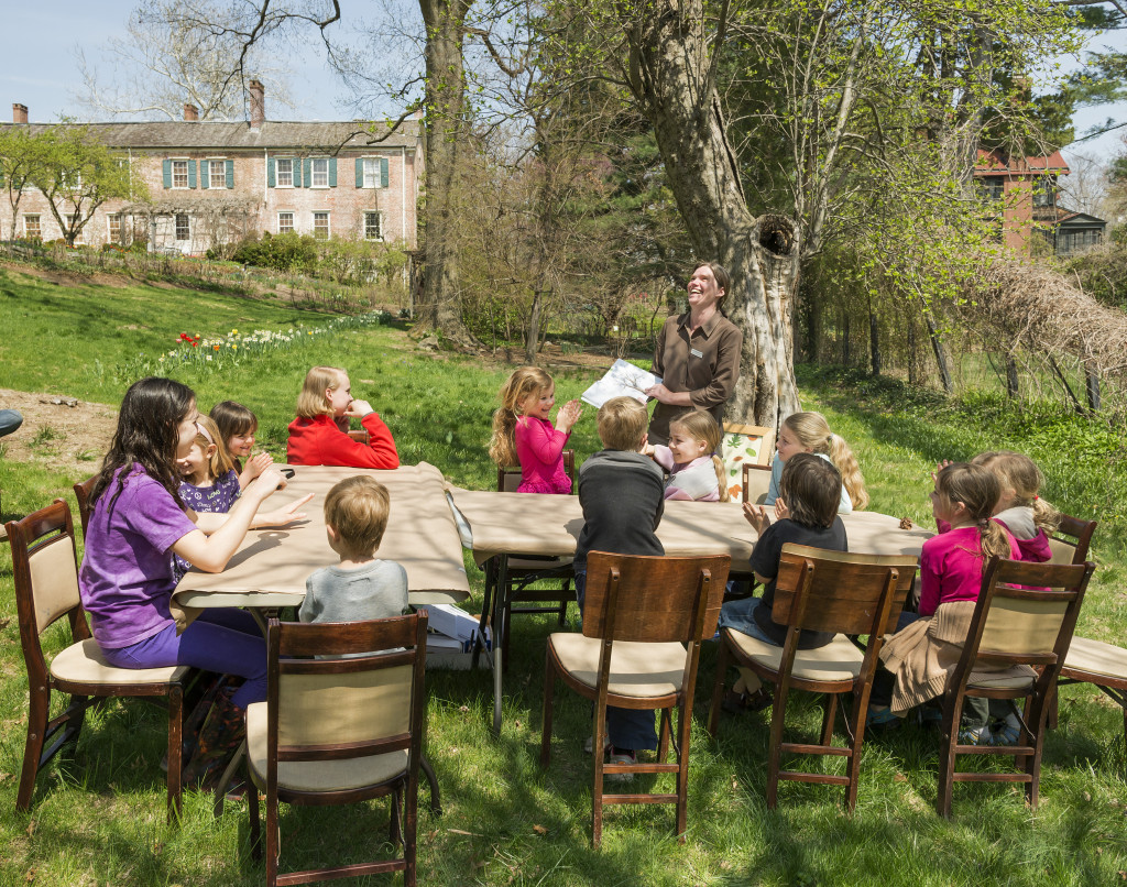 Several children sit at a table in the garden