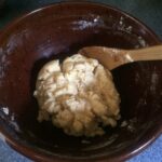 Cookie dough in a mixing bowl with wooden spoon.