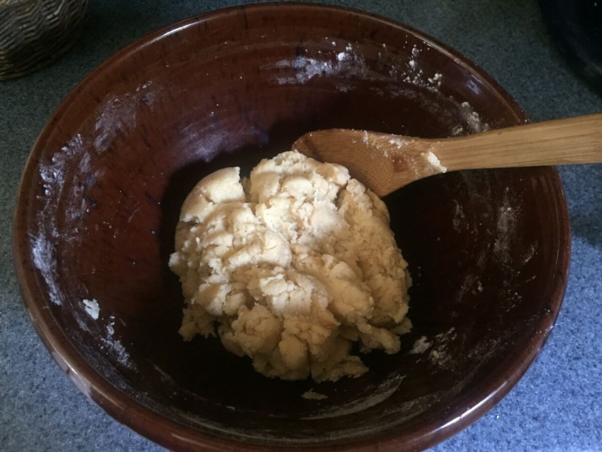 Cookie dough in a mixing bowl with wooden spoon.