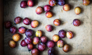 Several purple-red plums lay out on a board.