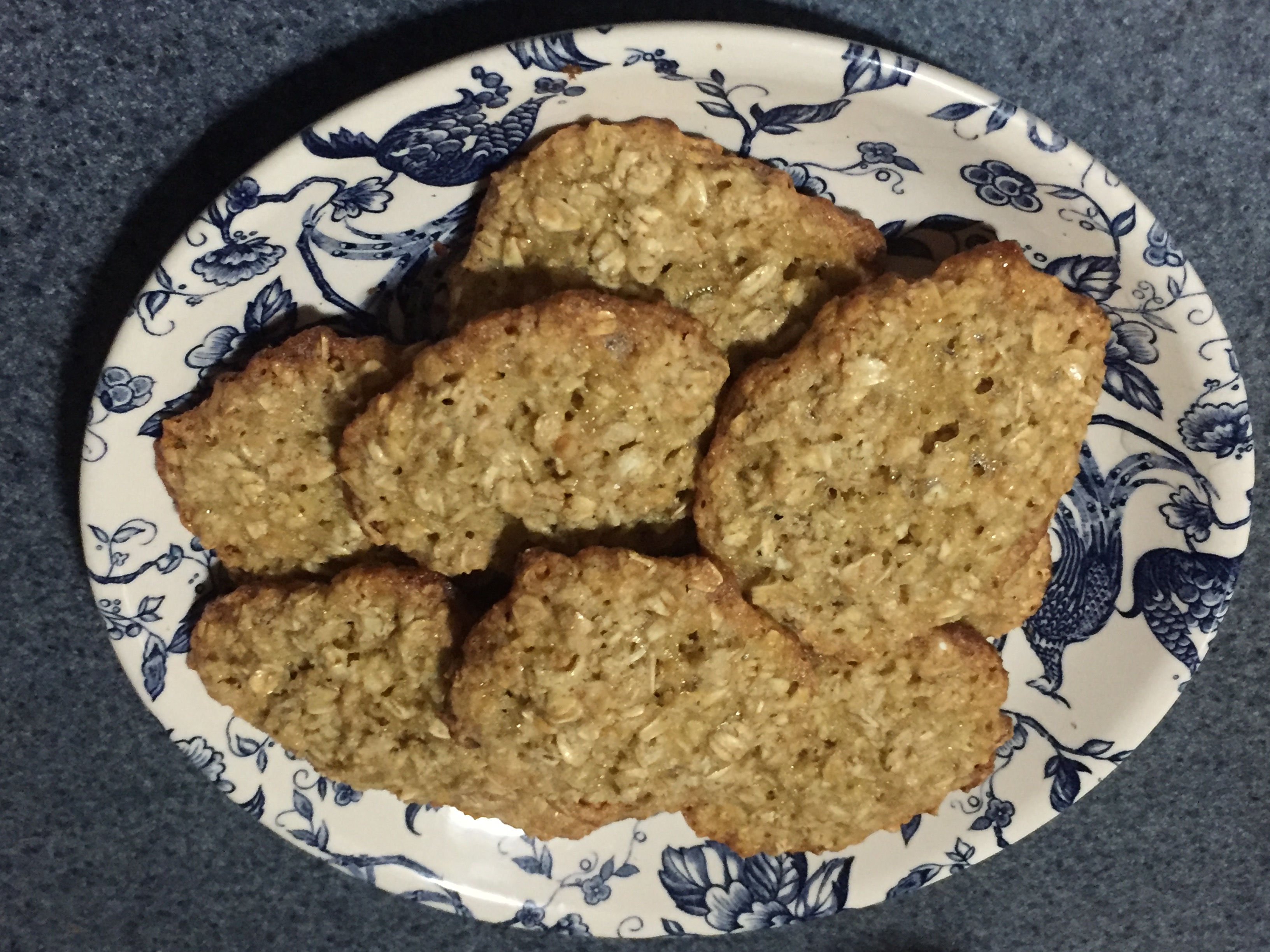 Ocho galletas de cacahuete marrón apiladas en un plato de porcelana azul y blanca.