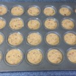 A mini muffin tin with 24 openings filled with unbaked batter.