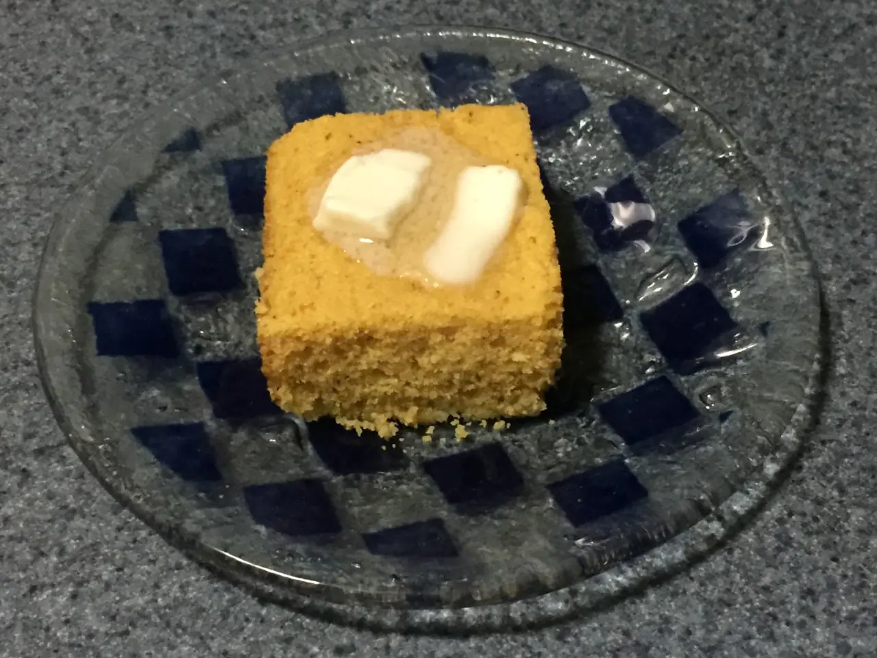 corn cake A square slice of yellow corn cake with melting butter on top.