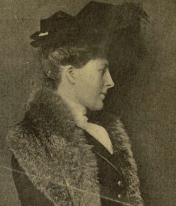 Photograph of Alice Duer Miller in profile. Her hair is pulled up and tucked under a hat. A fur stole drapes across her shoulders.