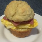 Taylor ham, egg and cheese on a muffin set on a white porcelain plate.