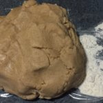 A ball of Cookie dough set next to flour ready to be rolled out.