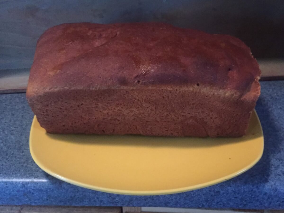A loaf of dark brown bread sits on top of a yellow plate.