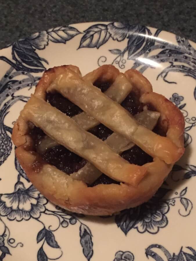 A small mince pie with hatch top sits on a decorative plate.