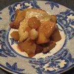 Un postre con manzanas, azúcar en polvo y hojaldre en un plato decorativo.