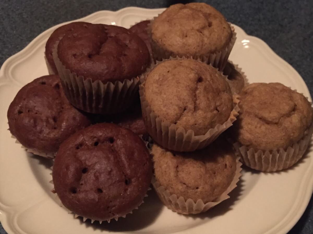 A decorative plate holds a pile of muffins. Muffins on the left are darker brown in color than muffins on the right.