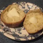Puffs for Breakfast with butter A baked puff sliced in half. Each half has melting butter spread on top.