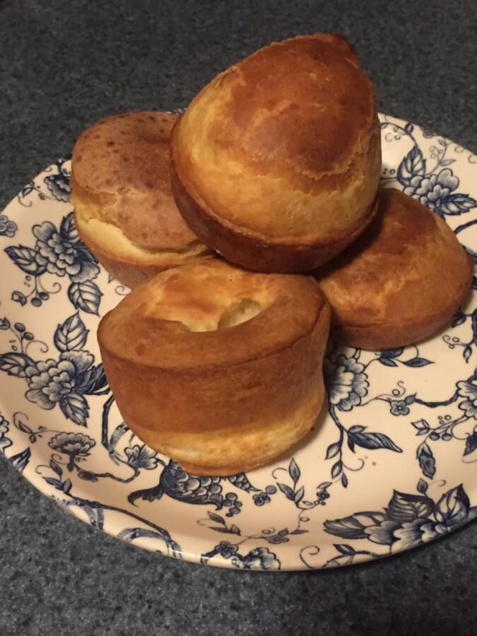 Four browned round bread puffs are stacked on a plate.