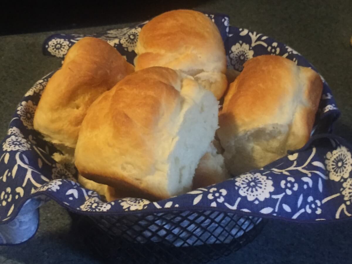Baked rolls with browned tops are stacked in a basket.