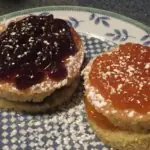 Two baked cakes layered with jelly and powdered sugar sit on top of a blue and white porcelain plate.