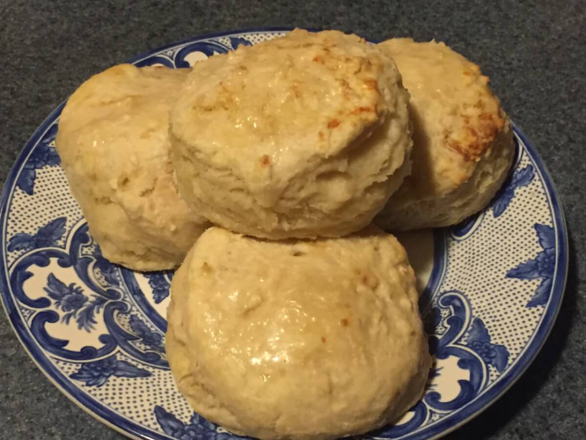 Round baked biscuits are stacked on top of a blue and white plate.