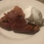Indian pudding2 A slice of a soufflé type dessert with whipped cream on a white plate.