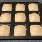 Tea cakes in pan A square baking pan with 9 square openings with baked tea cakes.