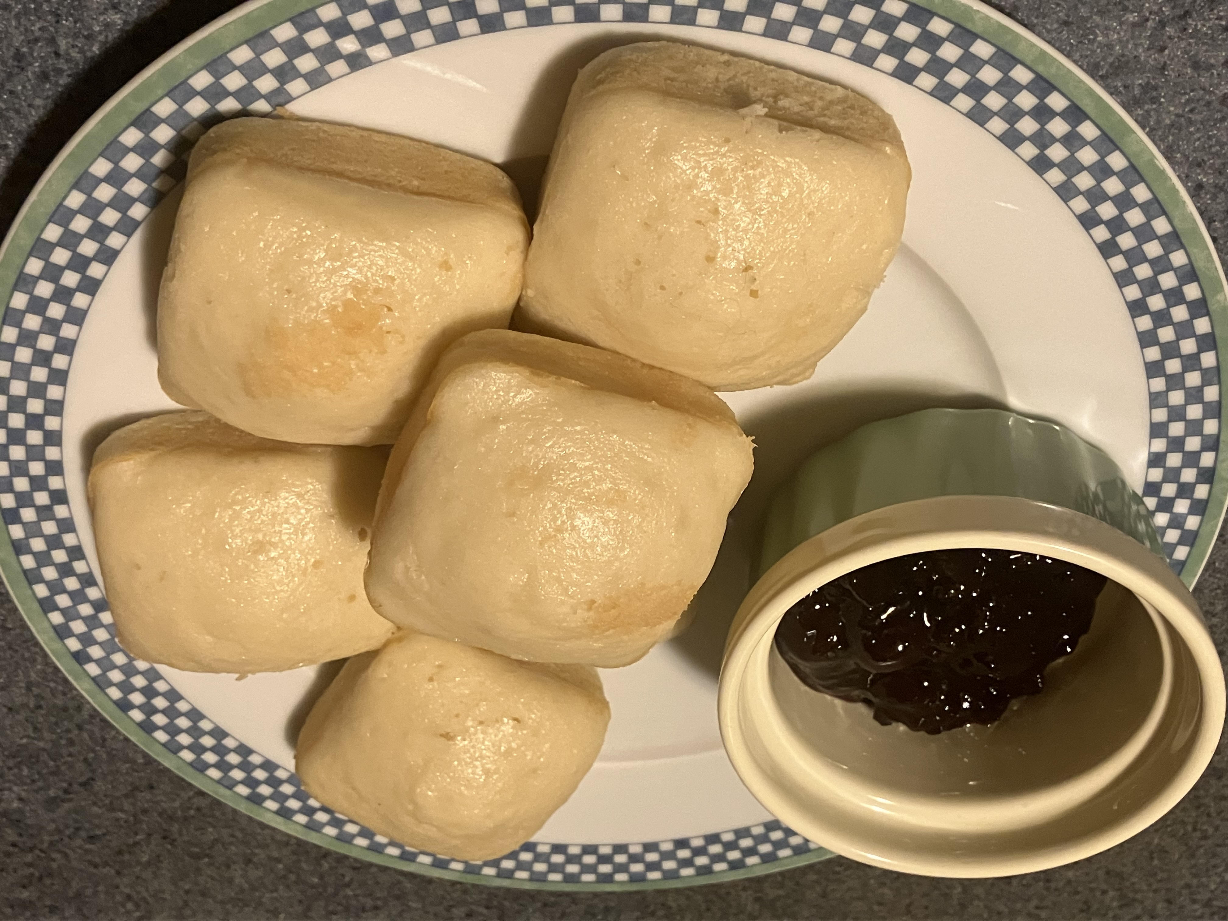 5 baked square tea cakes on a plate with a ramekin of cherry preserves.