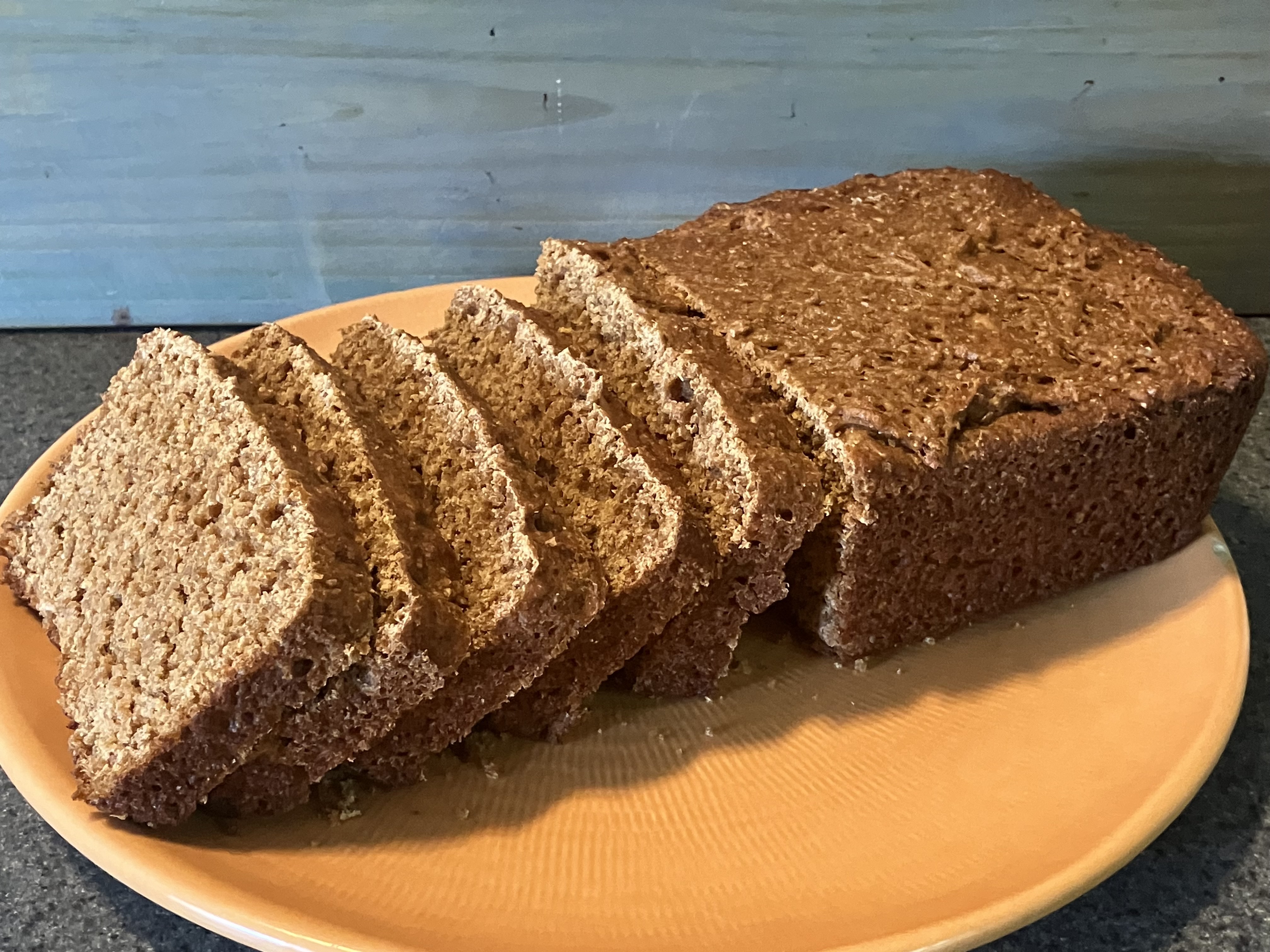 A loaf of bread that is sliced halfway through the loaf on a yellow plate.