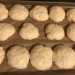 Unbaked rusk dough rising on a baking sheet.