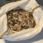 Plum pudding batter in a white pudding bag.