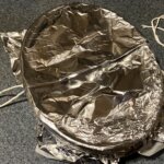 An oval bowl covered with foil and untied twine.