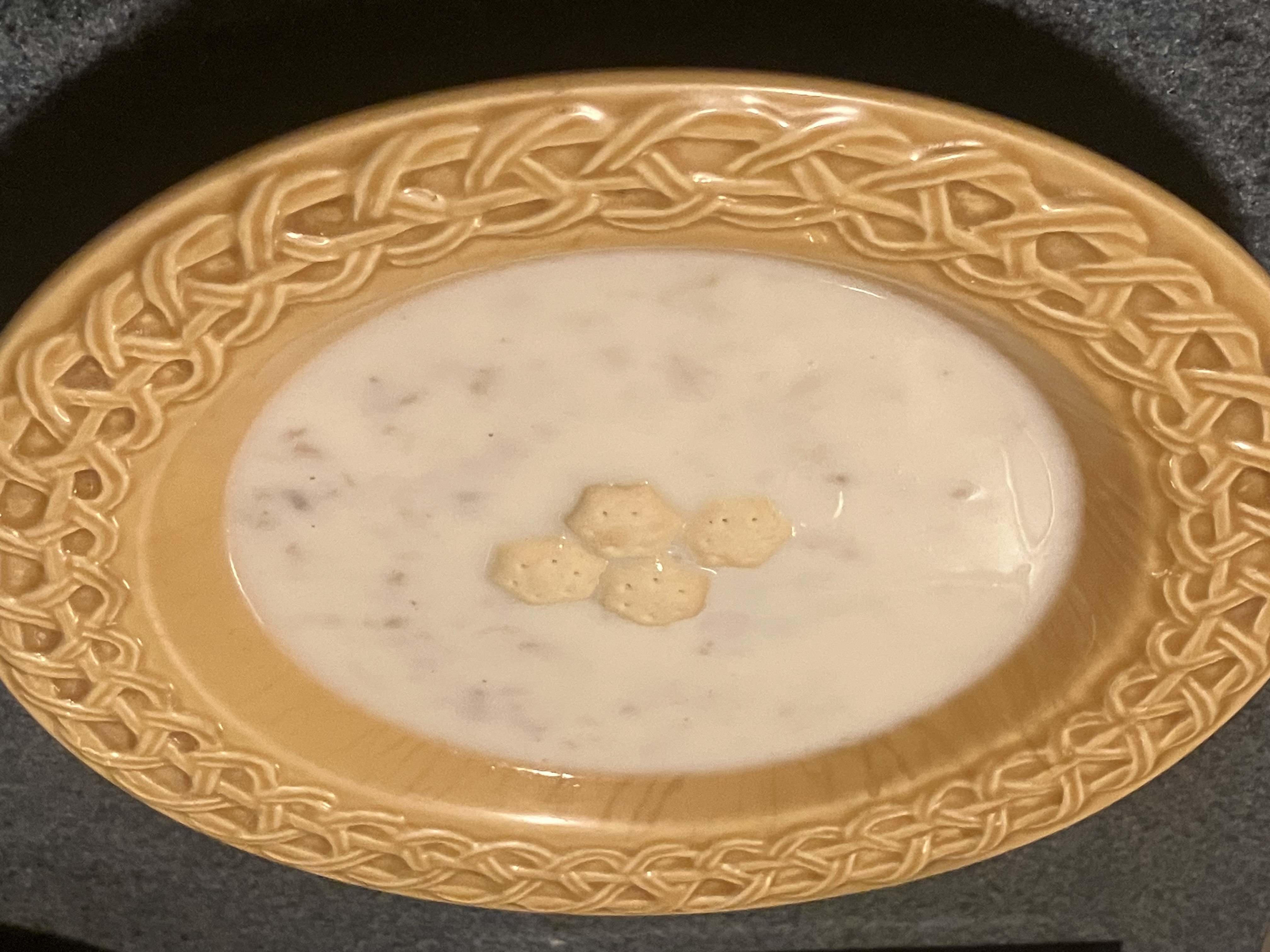 Creamy soup topped with crackers in a yellow bowl.